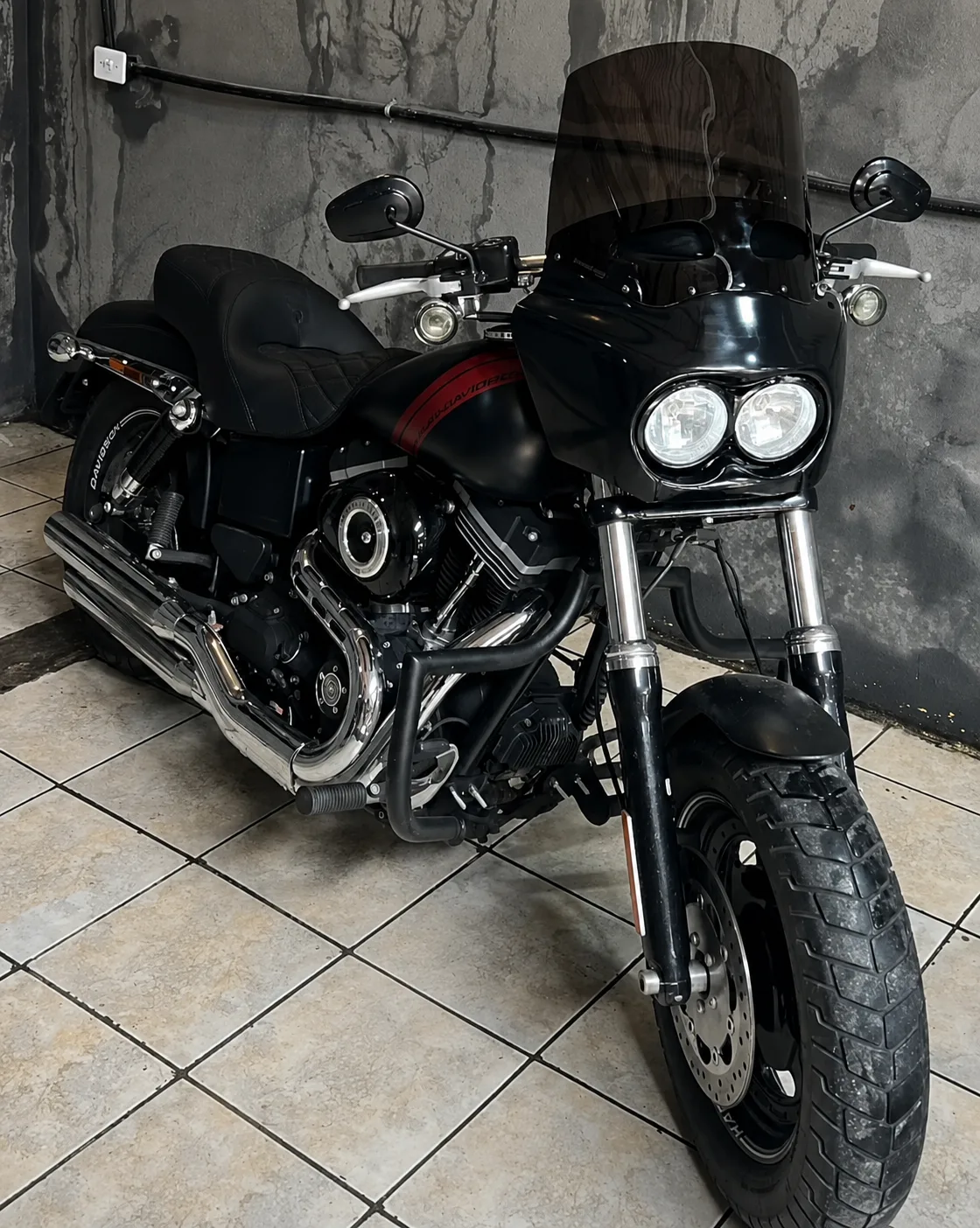 Fat Bob preta com fairing Memphis e bolha alta em ângulo frontal de três quartos
